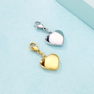 Detailed view of heart-shaped gold and silver stainless steel pendants with lobster clasps