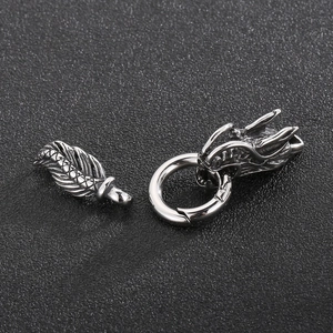 Macro detail of polished stainless steel dragon head clasp and silver feather pendant