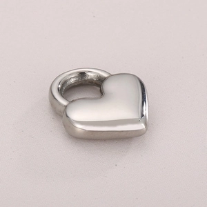 Polished silver hollow heart pendant in stainless steel on light fabric background