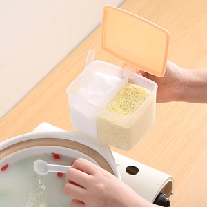 Dual-grid clear plastic seasoning box with orange lid and spoons for kitchen storage