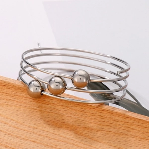 Detail of multi-layer stainless steel beaded bracelet on a minimalist wooden background