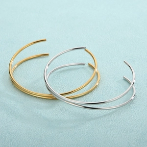 Macro shot of minimalist gold and silver titanium steel thin cuff bracelets layered together