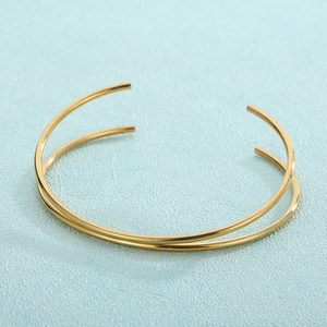 Detail of minimalist gold-plated titanium steel open bangle with parallel thin round bands