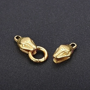 Macro detail of gold snake head jewelry clasps with intricate scale textures on black