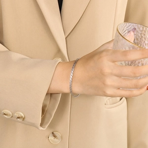 Minimalist silver braided stainless steel bracelet worn by a model with a glass cup
