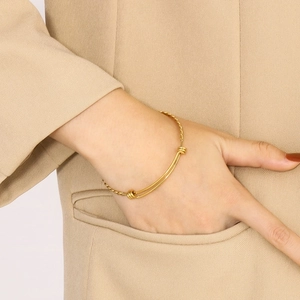 Detailed close-up of a gold minimalist twisted bangle with adjustable sliding knots
