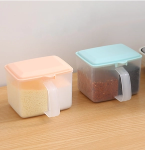 Detail of pink and blue divided seasoning boxes with spoons and flip lids on a wooden desk