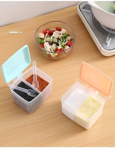 Close-up of divided kitchen spice box with blue and pink lids and serving spoons