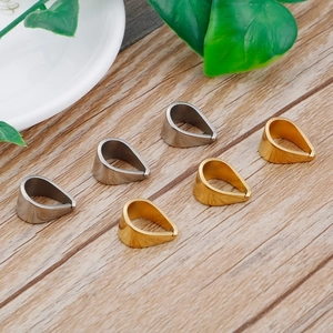 Macro shot of gold and silver teardrop pendant clasps on natural wood surface