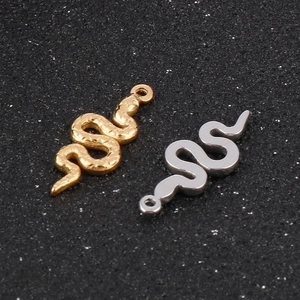 Macro view of gold snake charm with scale texture and silver smooth snake pendant set