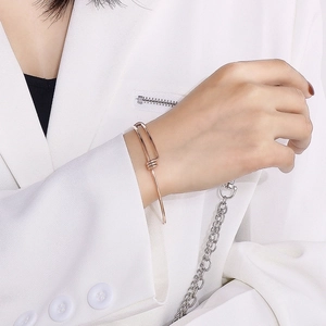 Detail of minimalist rose gold adjustable wire bracelet on woman's wrist in white blazer