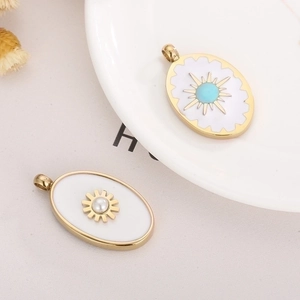 Close-up of gold oval pendants with sunburst patterns, turquoise and pearl on white enamel