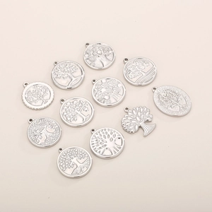 Detailed view of ten silver tree of life pendants in hollow and embossed round designs