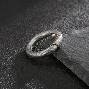 Macro shot of silver stainless steel spring ring with detailed snake scale pattern texture