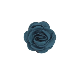 Detail view of a teal blue handmade satin camellia flower with layered fabric petals