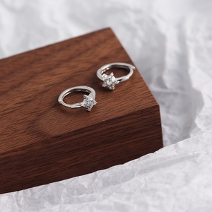 Macro shot of silver S925 huggie earrings with sparkling star shaped zircon inlay