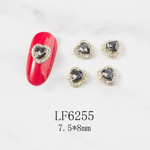 Macro detail of heart nail charm LF6255 with grey stone and gold frame on nails