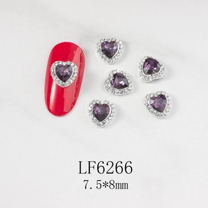 Macro detail of heart-shaped nail gems with purple stones and silver rhinestones