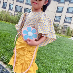 Détail d'un sac à bandoulière fleur rose et bleu sur la tenue d'un enfant mannequin