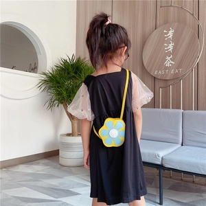 Sac bandoulière enfant en forme de fleur jaune et bleue, porté par un petit mannequin