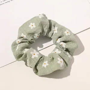 Close-up of light green floral scrunchie with daisy print on bubble crepe fabric