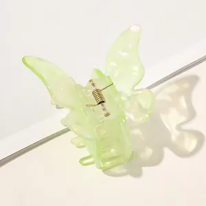 Close-up of butterfly hair claw in iridescent green acetate with gold spring mechanism