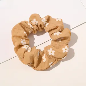Detail showing vintage yellow floral daisy pattern fabric scrunchie with elastic texture