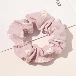 Detailed view of pink floral scrunchie with daisy patterns on seersucker fabric