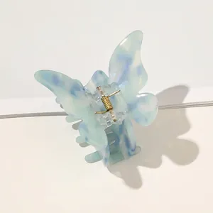 Close-up of light blue marble acetate butterfly hair claw clip with golden metal spring