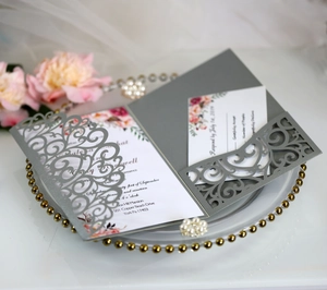 Detail of laser-cut grey wedding invitation set with floral inner card and reply card