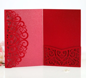 Detailed laser-cut pattern on a red paper wedding invitation cover with soft lighting
