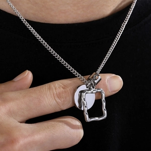 Close-up of silver geometric circle and rectangle pendant necklace on black shirt