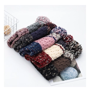 Detail view of colorful chunky knit beanies with faux fur pom-poms in various solid shades