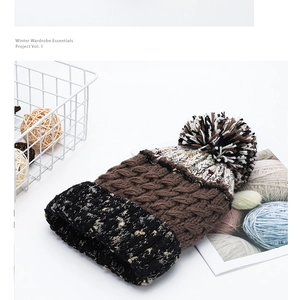 Detail of chunky knit beanie with color blocking design and fuzzy pom-pom top