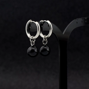 Macro shot of silver stainless steel hoop earrings with glossy black sphere charms