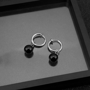 Detail showing clip-on earrings with polished black beads and silver rings for women