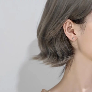 Minimalist silver stud earrings shown on ear for a delicate and subtle daily style