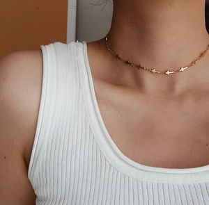 Close-up of a gold cross choker necklace worn on model's neck for layered style