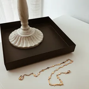 Detailed view of golden cross chain necklace with lobster clasp on a white surface