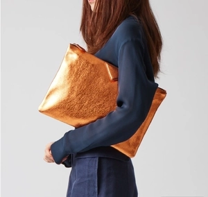 Macro shot of metallic orange glitter envelope clutch with secure top metal zipper closure
