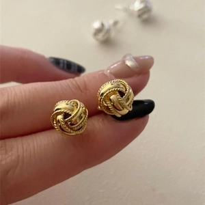 Pendientes de nudo dorado en plata S925 que muestran el tamaño pequeño en el dedo