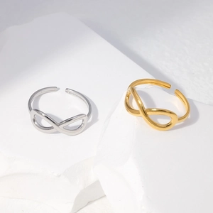 Close-up of infinity symbol open rings in gold and silver finish on white stones