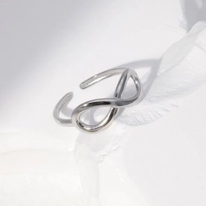 Macro shot of silver infinity shaped stainless steel open ring on white stone base