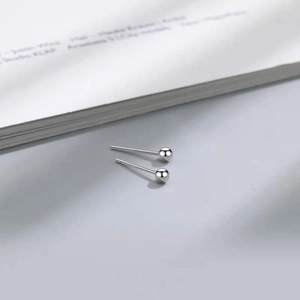 Minimalist S999 sterling silver ball earrings shown in a clean, high-quality flat lay view