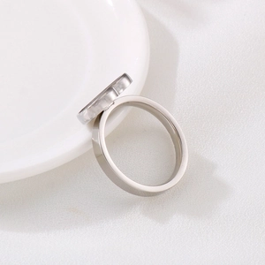 Macro side view of silver stainless steel heart base ring resting on white ceramic tray
