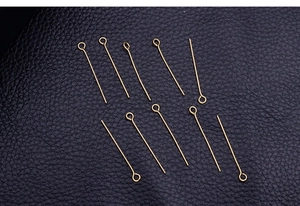 Detailed view of ten golden stainless steel eye pins on black textured leather surface