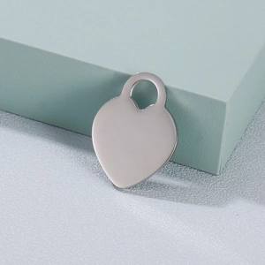 Polished silver heart pendant made of stainless steel displayed on a geometric stand