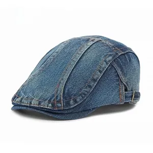 Detail of washed blue denim flat cap featuring contrast orange stitching and side buckle