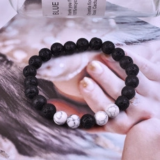 Close-up of black lava rock beads and white marble stones on an elastic bracelet