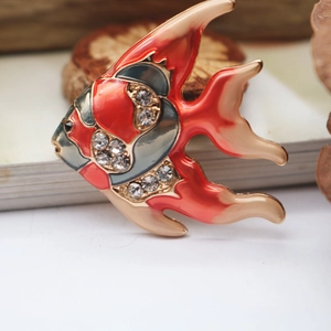 Detailed close-up of a tropical fish brooch with orange enamel and sparkling crystals